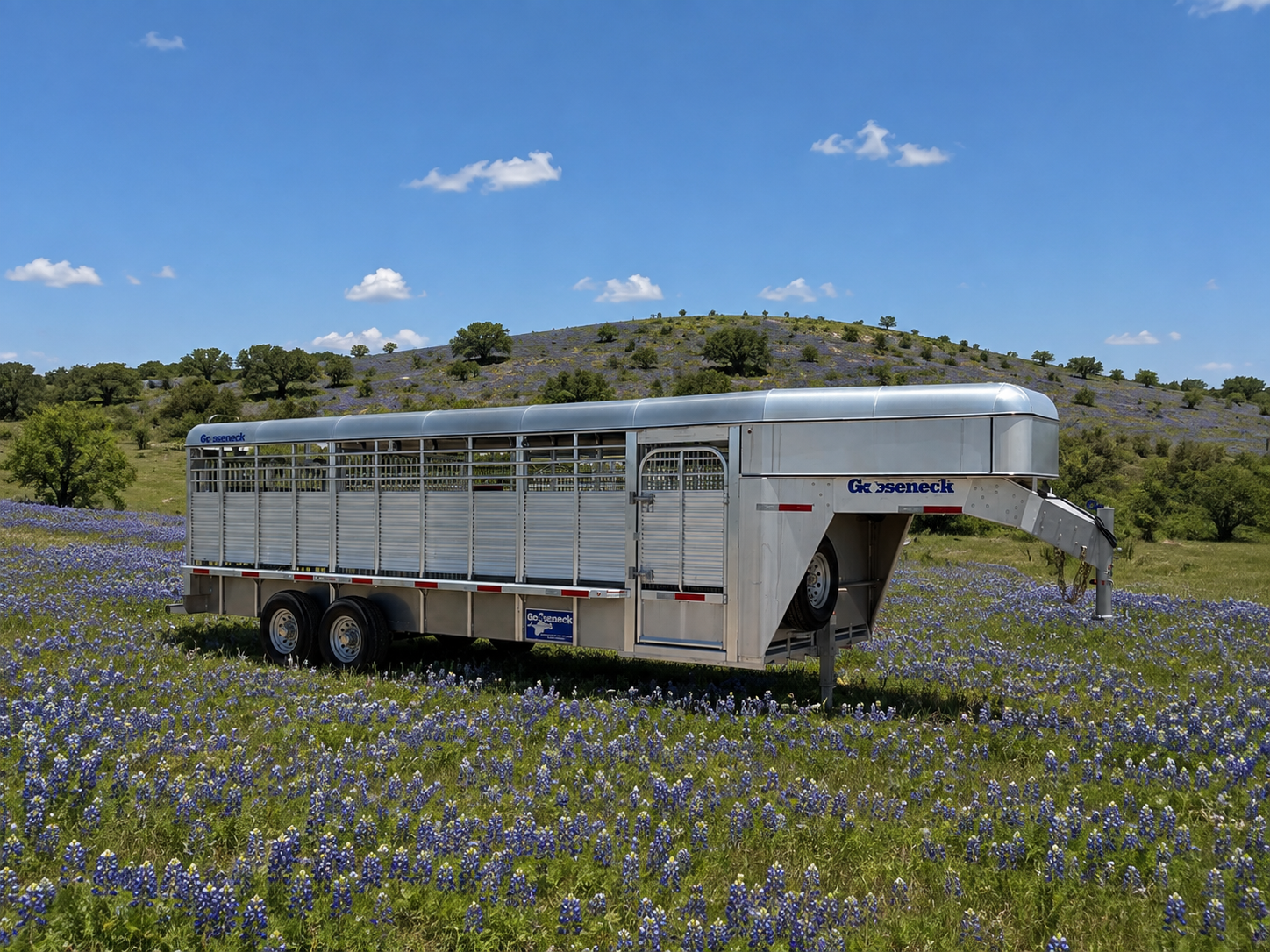 Aluminum stock gooseneck trailer with five-plank solid sides parked in a field of bluebonnets
